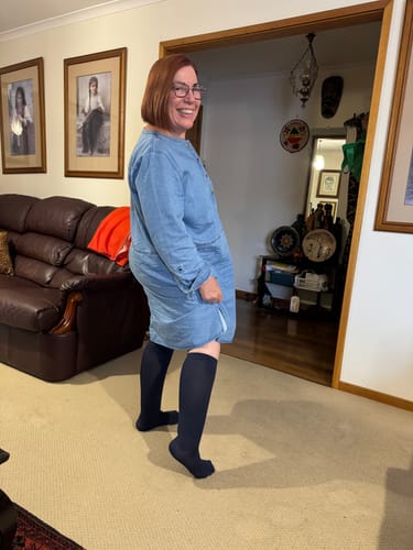 Reviewer smiling and wearing black Premium Bamboo Compression Socks in a living room setting.