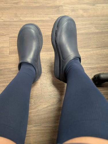 Customer's point-of-view wearing the blue Everstride™ Compression Socks with dark blue clogs.